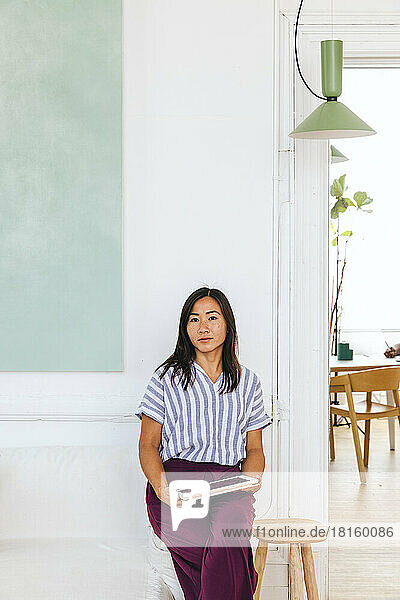 Porträt einer selbstbewussten  kreativen Geschäftsfrau  die mit einem iPad auf dem Sofa sitzt