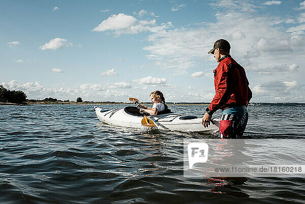 father teaching his daughter to Kayak in the sea on a sunny day