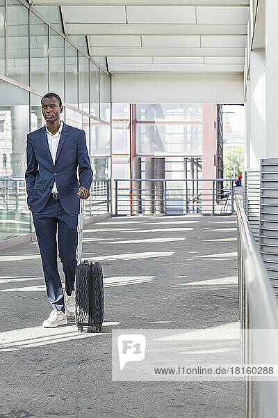 Young businessman walking with suitcase at railroad station