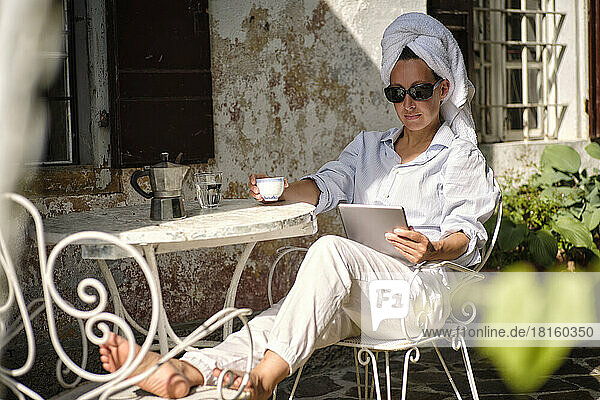 Woman with sunglasses watching tablet PC and having coffee at rooftop