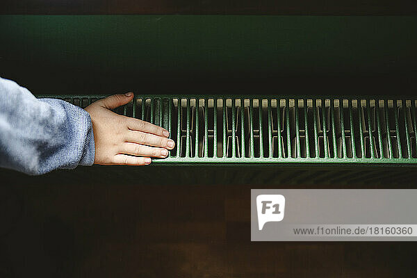 Hand of boy touching radiator at home