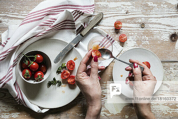 Hands of woman removing seeds from fresh homegrown tomatoes