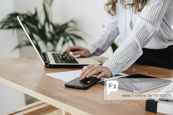 Young businesswoman working in modern office using laptop and smartphone. close up