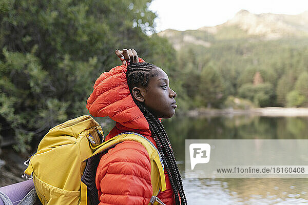 Young woman with backpack by lake at vacation