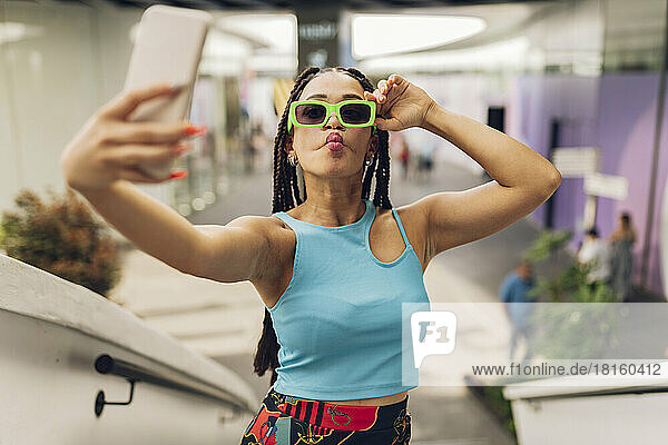 Young woman wearing sunglasses taking selfie through smart phone