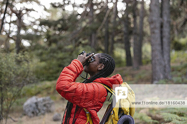 Woman with braided hair photographing in forest