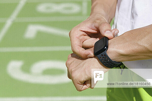 Mann überprüft Zeit auf Smartwatch an Sportstrecke