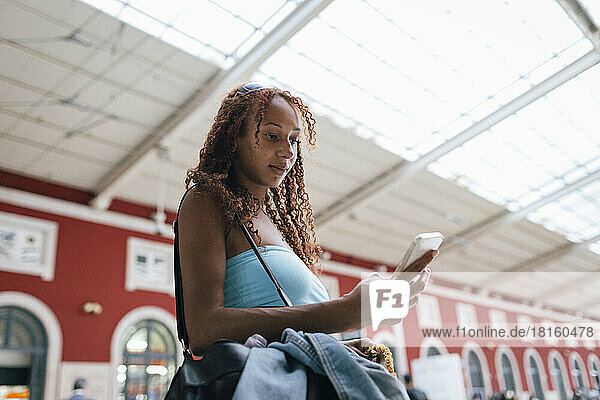 Woman using smart phone standing at railroad station