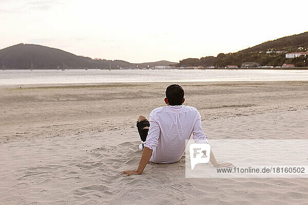 Young man relaxing at beach watching sunset