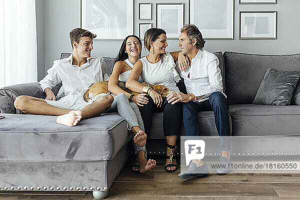 Smiling parents and children with dog on sofa at home