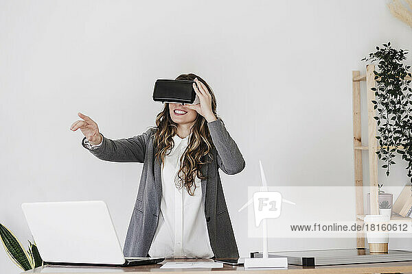 Gesturing young businesswoman using virtual reality simultor in office
