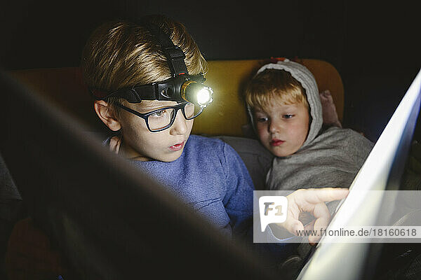 Junge trägt Scheinwerfer und liest Buch mit Bruder zu Hause