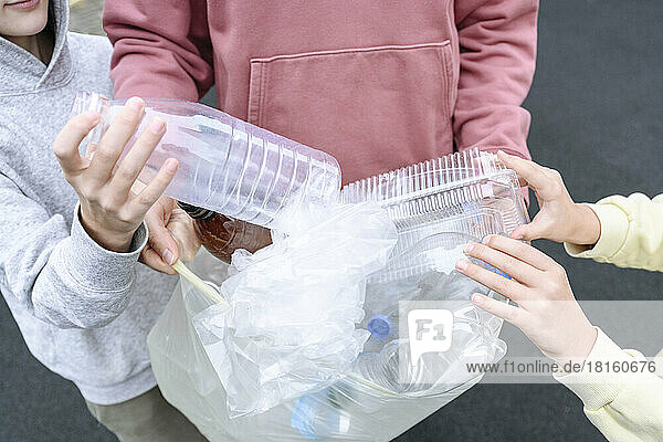 Hände von Menschen und Kindern sammeln Plastikmüll