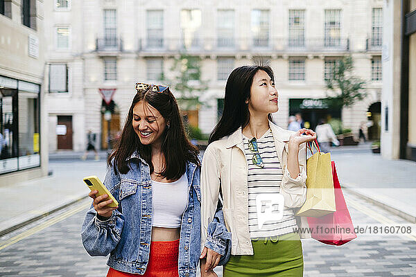 Woman exploring city with lesbian friend using smart phone