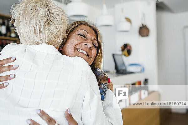 Happy businesswoman hugging friend at restaurant