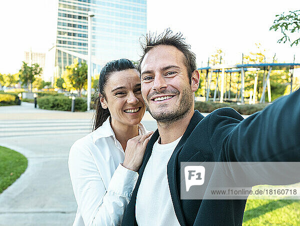 Happy businesswoman with colleague taking selfie at office park