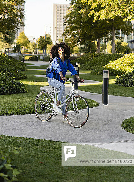 Happy woman with bicycle on footpath at park
