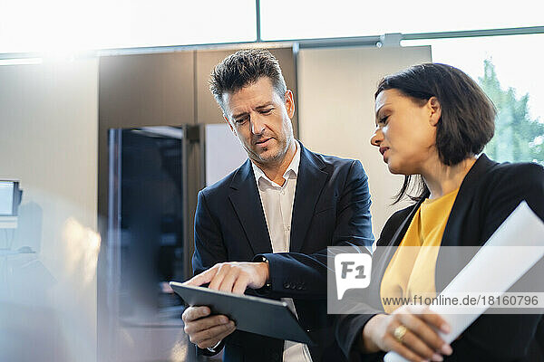 Geschäftsmann und Geschäftsfrau diskutieren über Tablet-PC im Büro