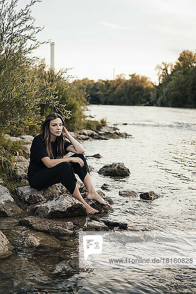 Contemplative young woman sitting near lake