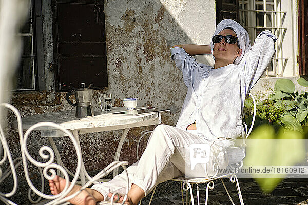 Woman wearing towel and sunglasses relaxing on terrace