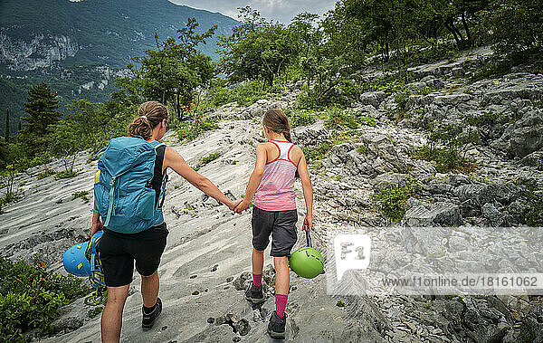 Woman holding daughter's hand walking on mountain