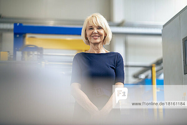 Happy senior businesswoman standing in factory