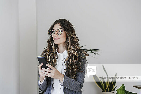 Thoughtful businesswoman using mobile phone in office