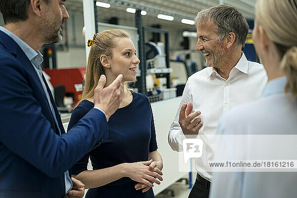 Happy senior businessman discussing with colleagues at industry