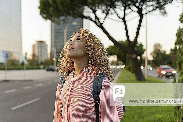 Thoughtful blond woman with backpack on street