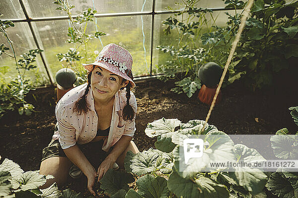 Smiling mature farmer wearing hat in greenhouse