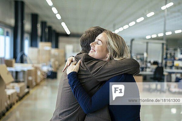 Smiling businesswoman embracing colleague in industry