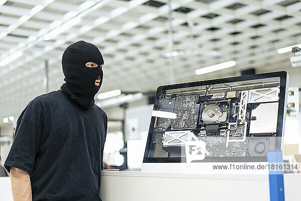 Robber standing by computer at warehouse