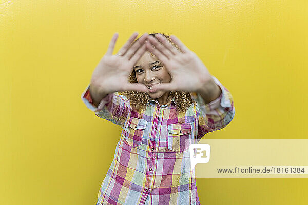 Smiling woman gesturing over yellow background