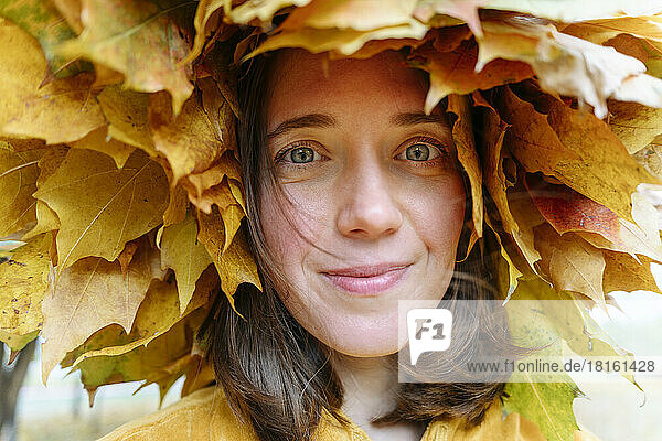 Lächelnde Frau mit grauen Augen  die einen Herbstlaubkranz trägt