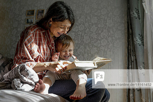 Happy mother with baby reading book at home