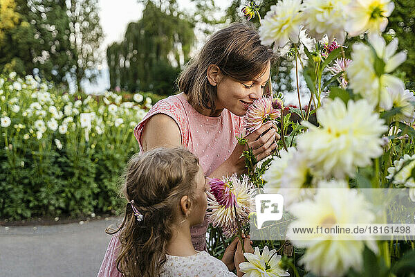 Mother and daughter smelling flowers in garden
