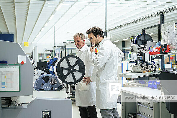 Businessmen examining machine in industry