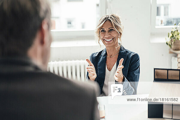 Excited real estate agent gesturing and talking to client at office