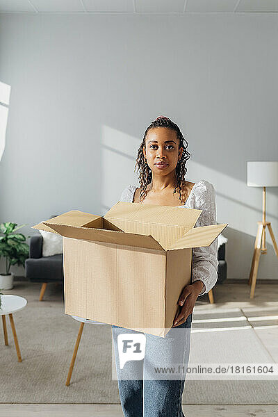 Woman carrying cardboard box standing in new house
