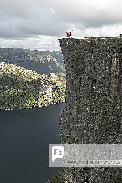 Hikers standing on edge of Pulpit rock cliff by Lysefjorden fjord  Norway