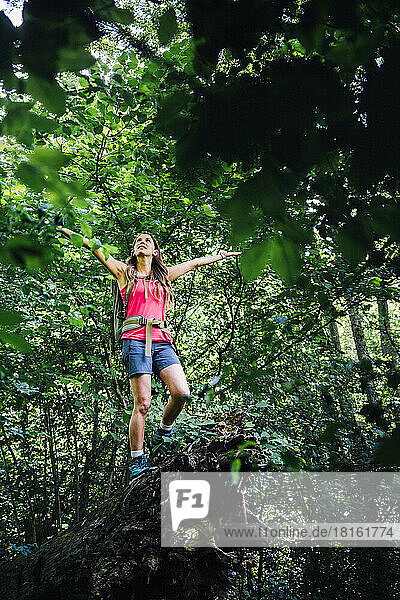 Woman with arms outstretched enjoying nature in forest