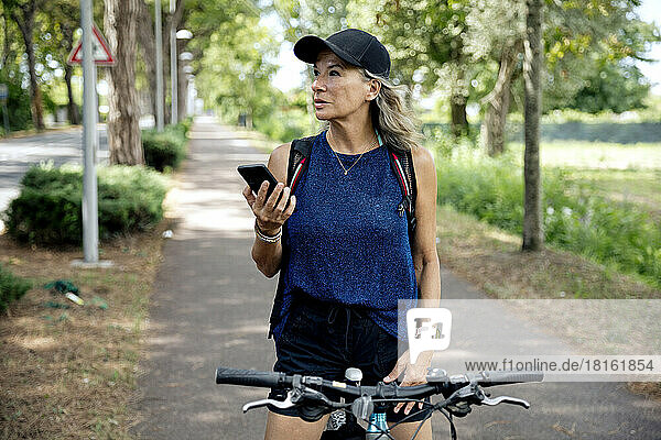 Senior woman holding mobile phone on bicycle