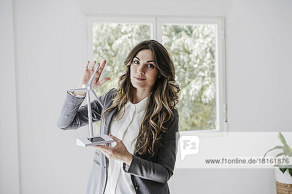 Female entrepreneur standing in office holding windturbine model