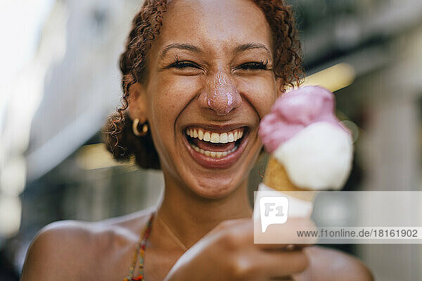 Fröhliche junge Frau  die Spaß mit Eis in der Hand hat
