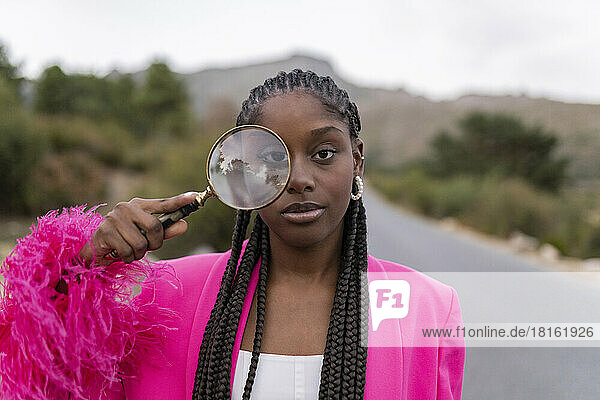 Young woman with magnifying glass on road