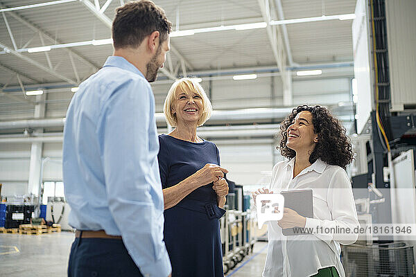 Happy businesswoman discussing with colleagues in industry