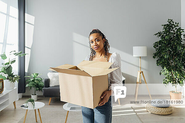 Young woman with cardboard box standing in new house