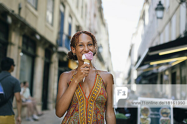 Smiling young woman licking ice cream