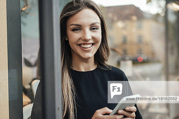 Cheerful young woman with long hair holding smart phone