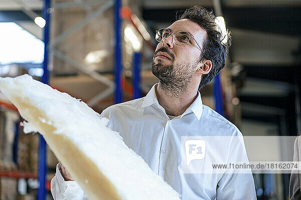 Businessman holding insulation at warehouse